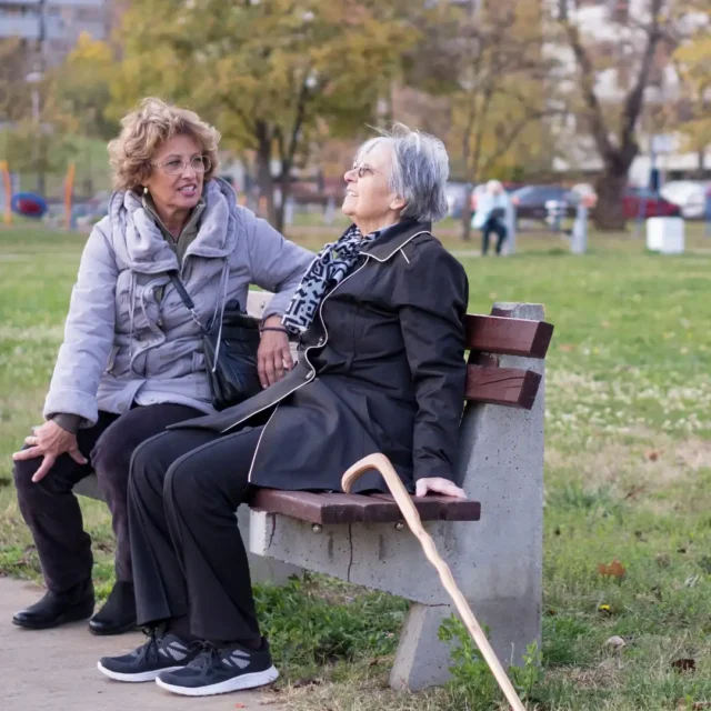 Photo of a carer and elderly lady sat on a bench - Leah Care support services